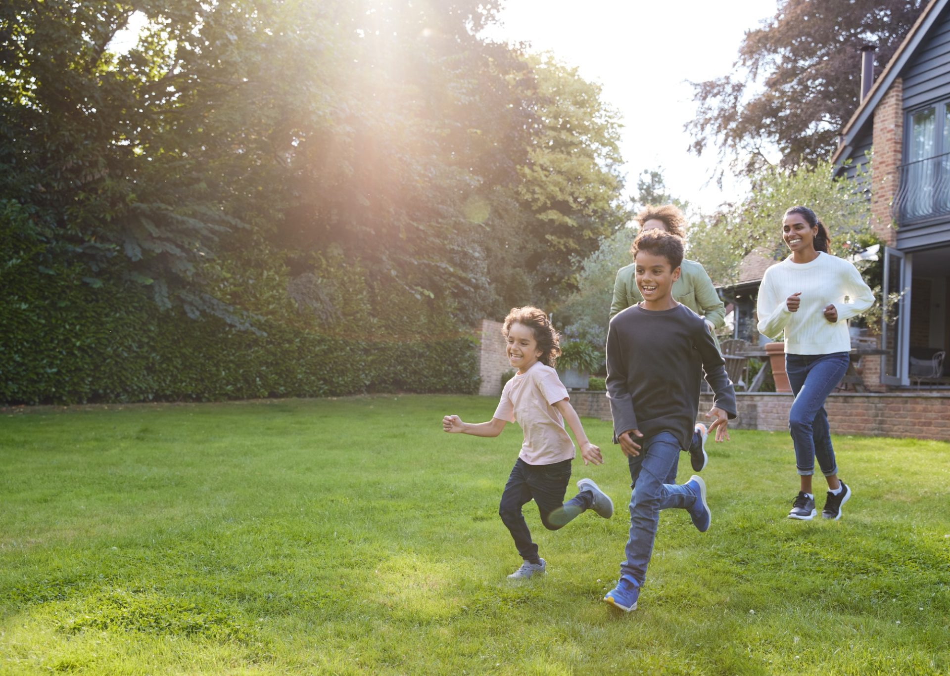 Family running on lawn outside house